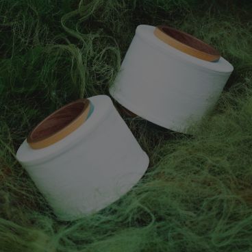 Spools of Hyosung’s recycled nylon and polyester yarn placed on a green discarded fishing net