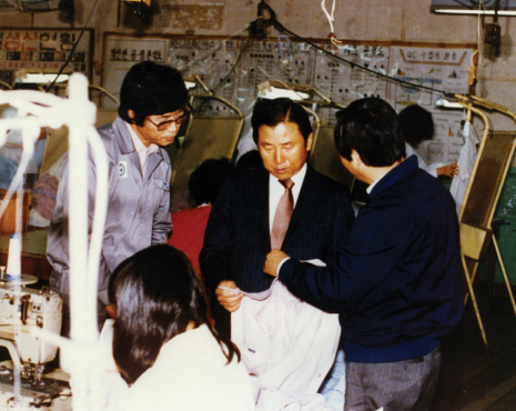 경영진이 섬유 생산 공장을 직접 방문하여 직원들과 함께 제품의 품질을 꼼꼼히 확인하는 모습